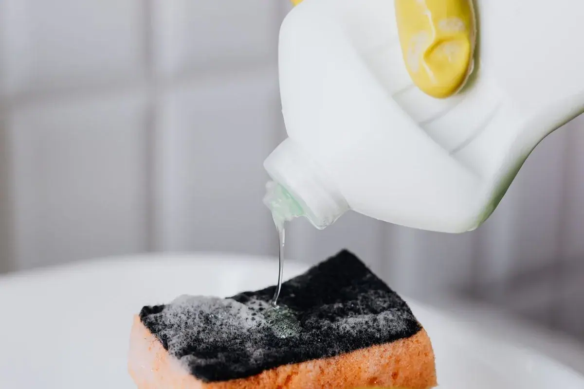 Detergente neutro sendo aplicado em uma esponja para lavar cesto e gaveta da air fryer