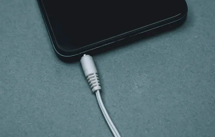 Celular conectado ao cabo de carregamento sobre superfície azul