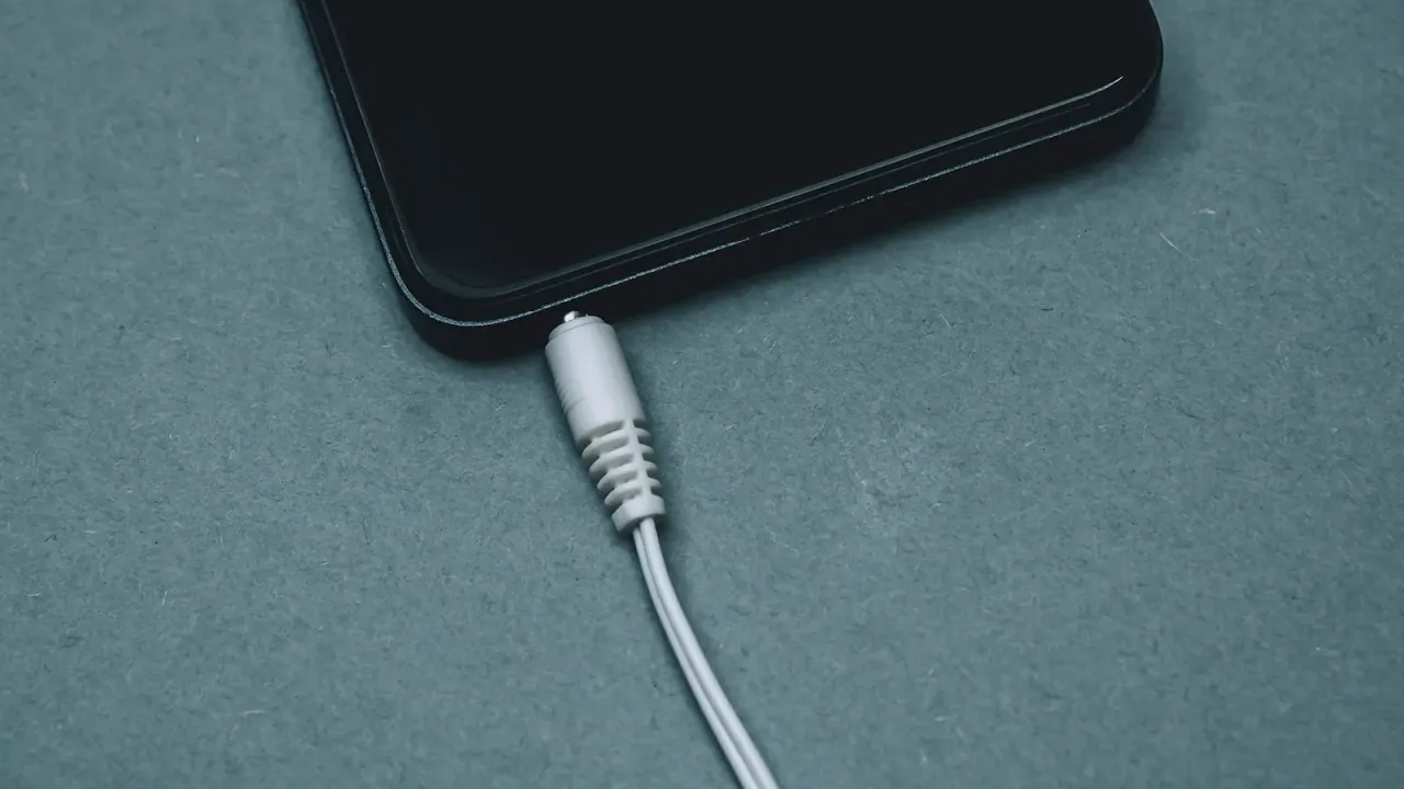 Celular conectado ao cabo de carregamento sobre superfície azul