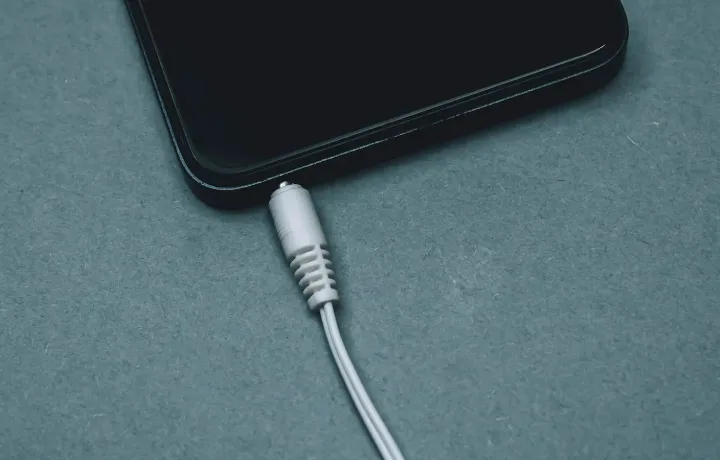 Celular conectado ao cabo de carregamento sobre superfície azul