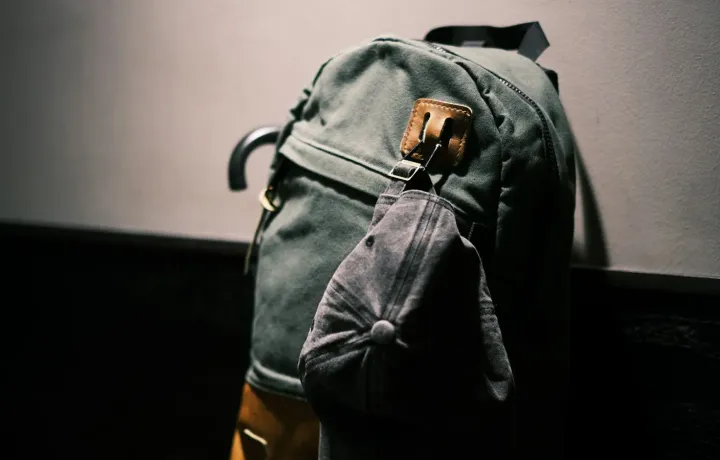Mochila preta apoiada sobre mesa de madeira