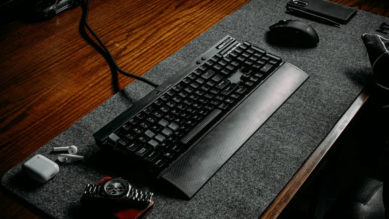Teclado e mouse sobre mouse pad preto em mesa de madeira