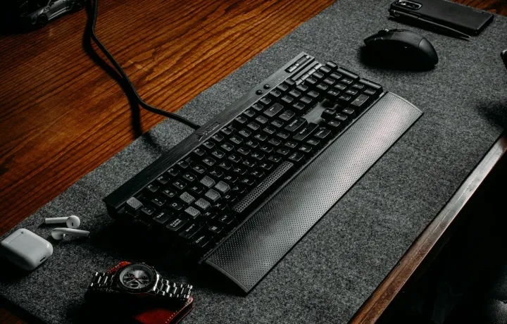 Teclado e mouse sobre mouse pad preto em mesa de madeira