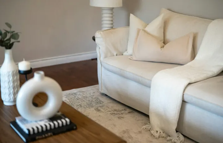 Sofá branco de tecido em sala clara com almofadas neutras