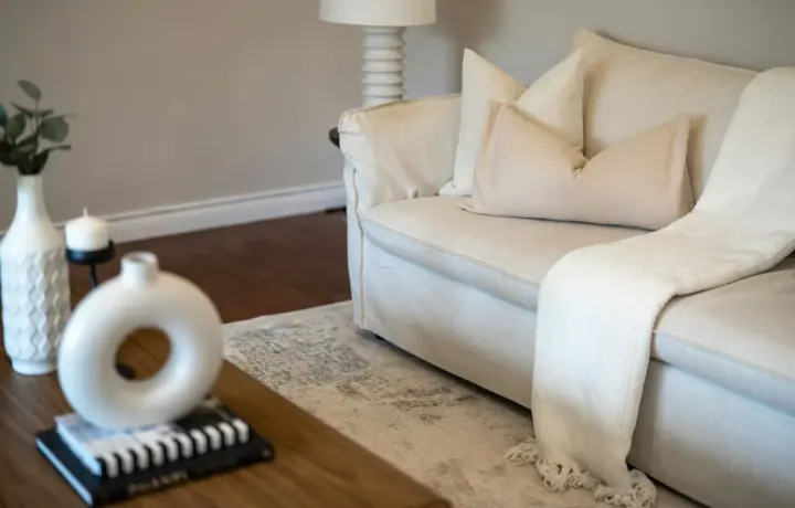 Sofá branco de tecido em sala clara com almofadas neutras