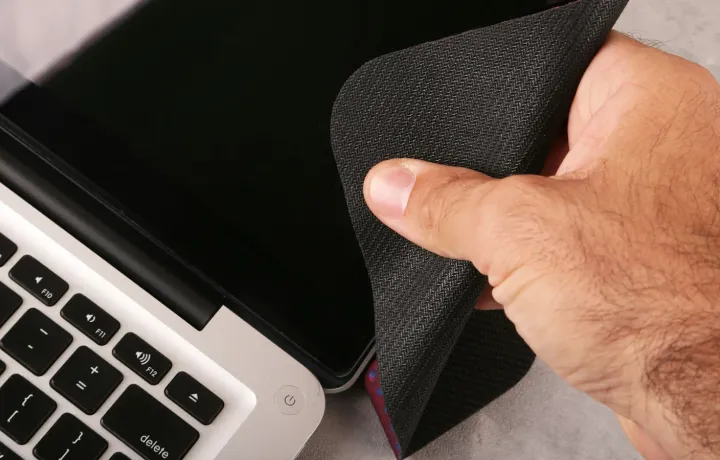 Mão passando pano de microfibra na tela de um notebook