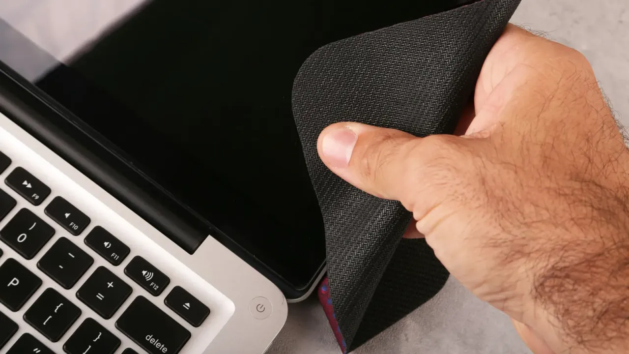 Mão passando pano de microfibra na tela de um notebook