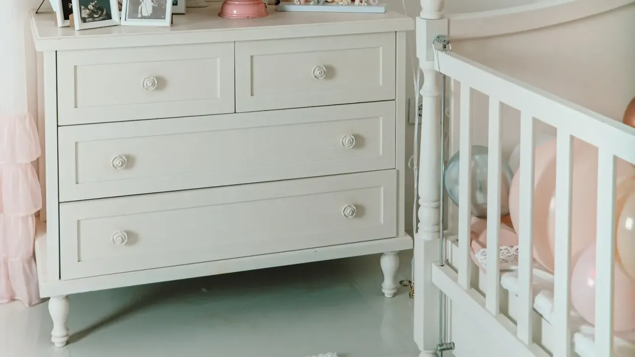 Quarto de bebê claro com cômoda branca ao lado do berço