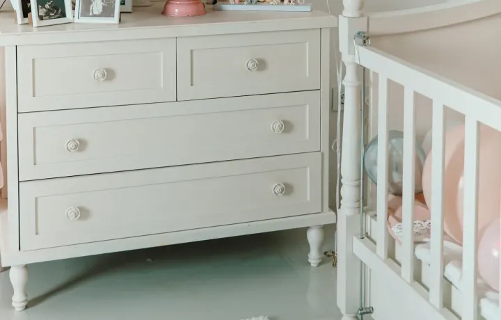 Quarto de bebê claro com cômoda branca ao lado do berço
