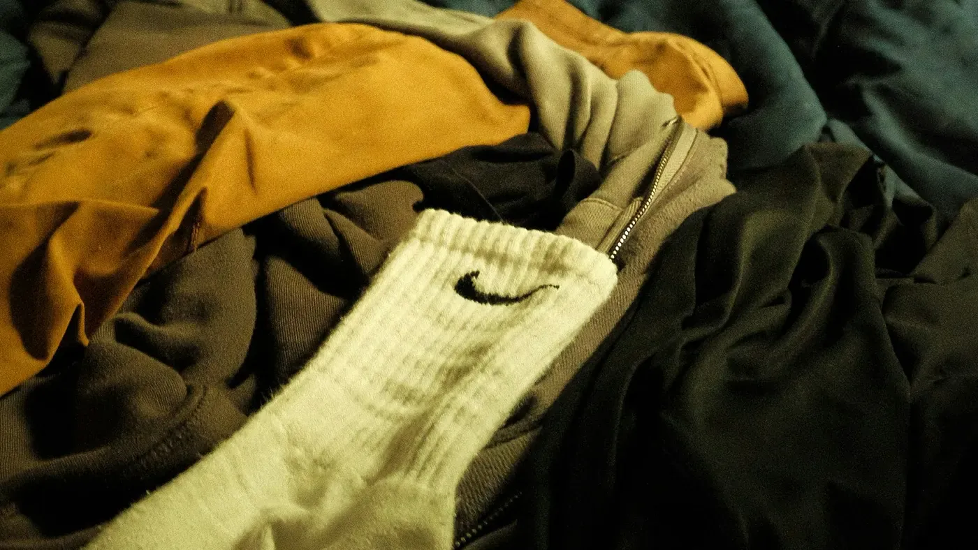 Pilha de roupas sobre uma cama durante a organização do guarda-roupa