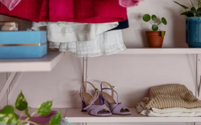Prateleira com roupas dobradas e sapatos organizados na parte inferior
