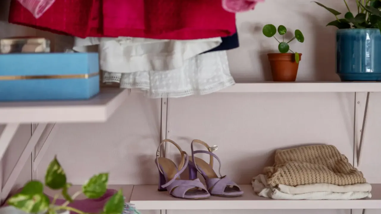 Prateleira com roupas dobradas e sapatos organizados na parte inferior